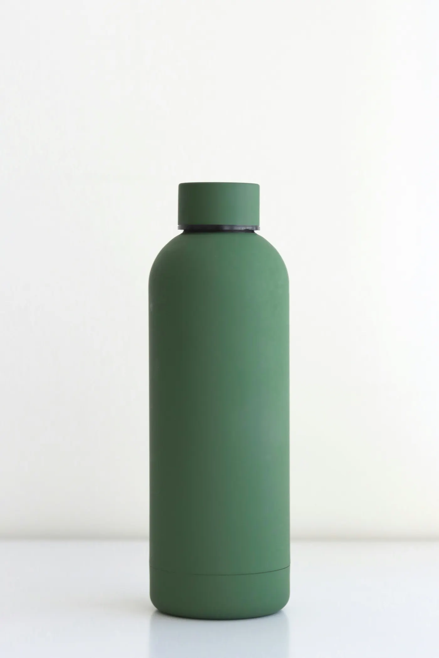 A green reusable water bottle on a white table