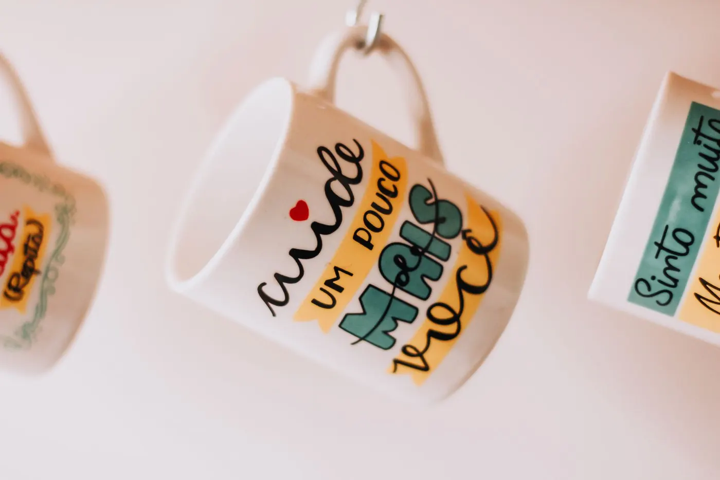 Ceramic mugs with printed text hanging in a row