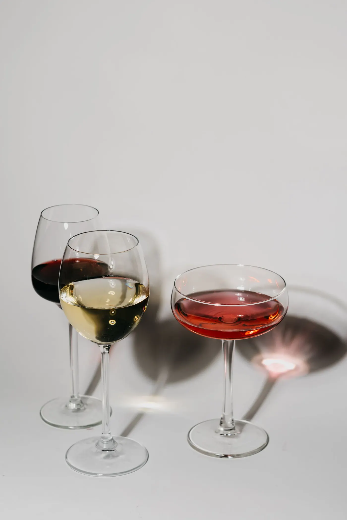 Wine glasses of red, white, and rosé on a light surface